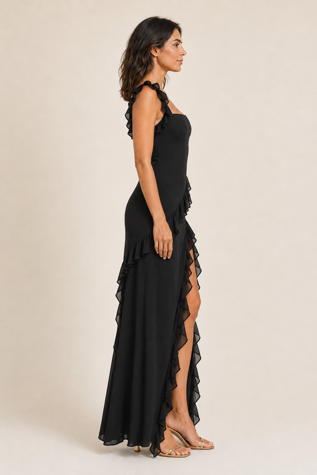 Side view of a woman wearing the black asymmetric ruffle high-slit maxi dress
