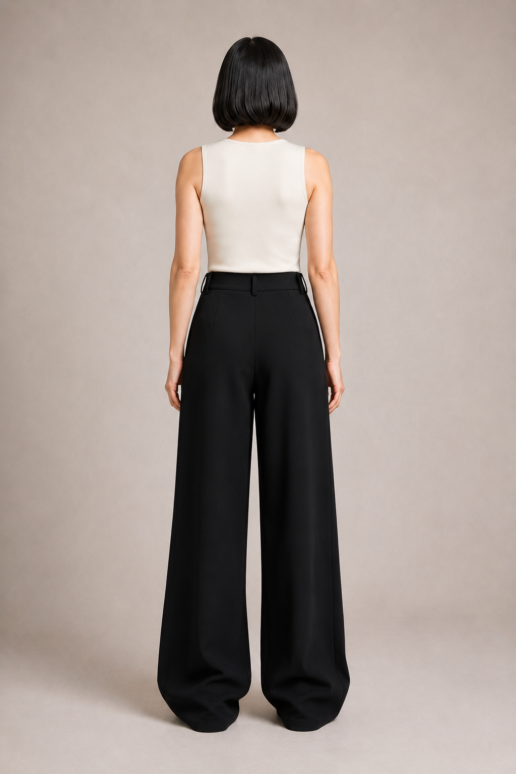 Back view of the black asymmetric-waist wide-leg trousers showing the clean waistband and wide legs
