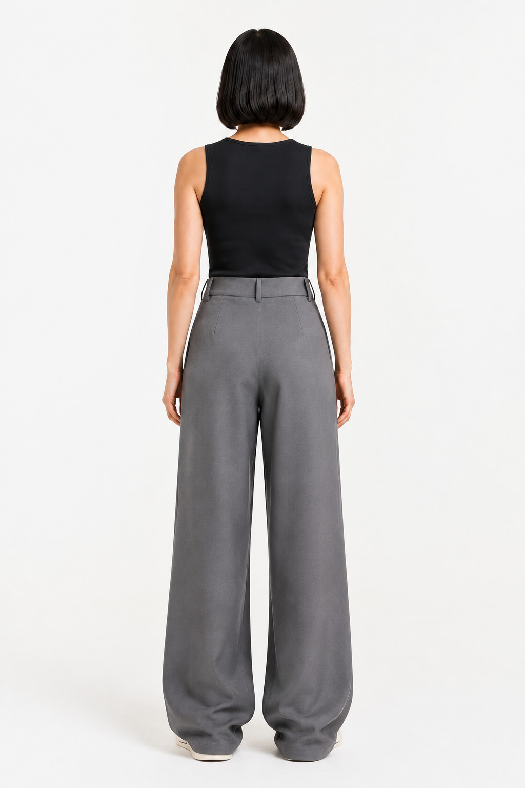 Back view of the grey asymmetric-waist wide-leg trousers showing the clean waistband and wide legs