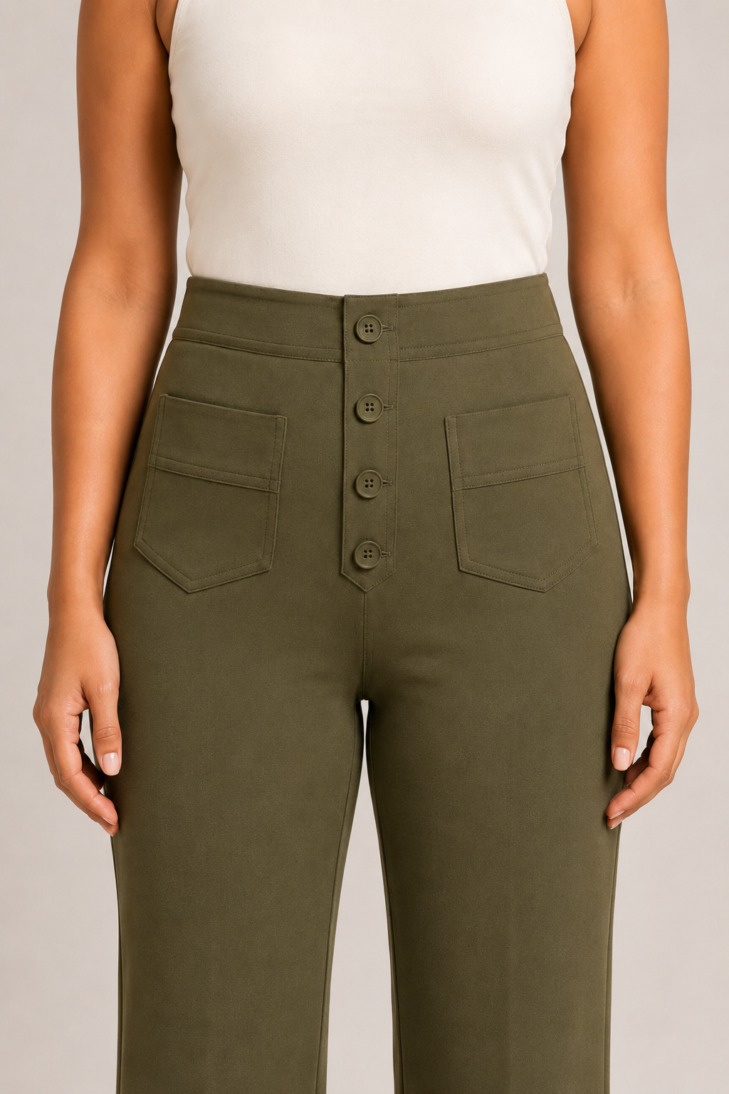 Close-up of the green trousers showing the four-button front placket, high waistband and patch pockets
