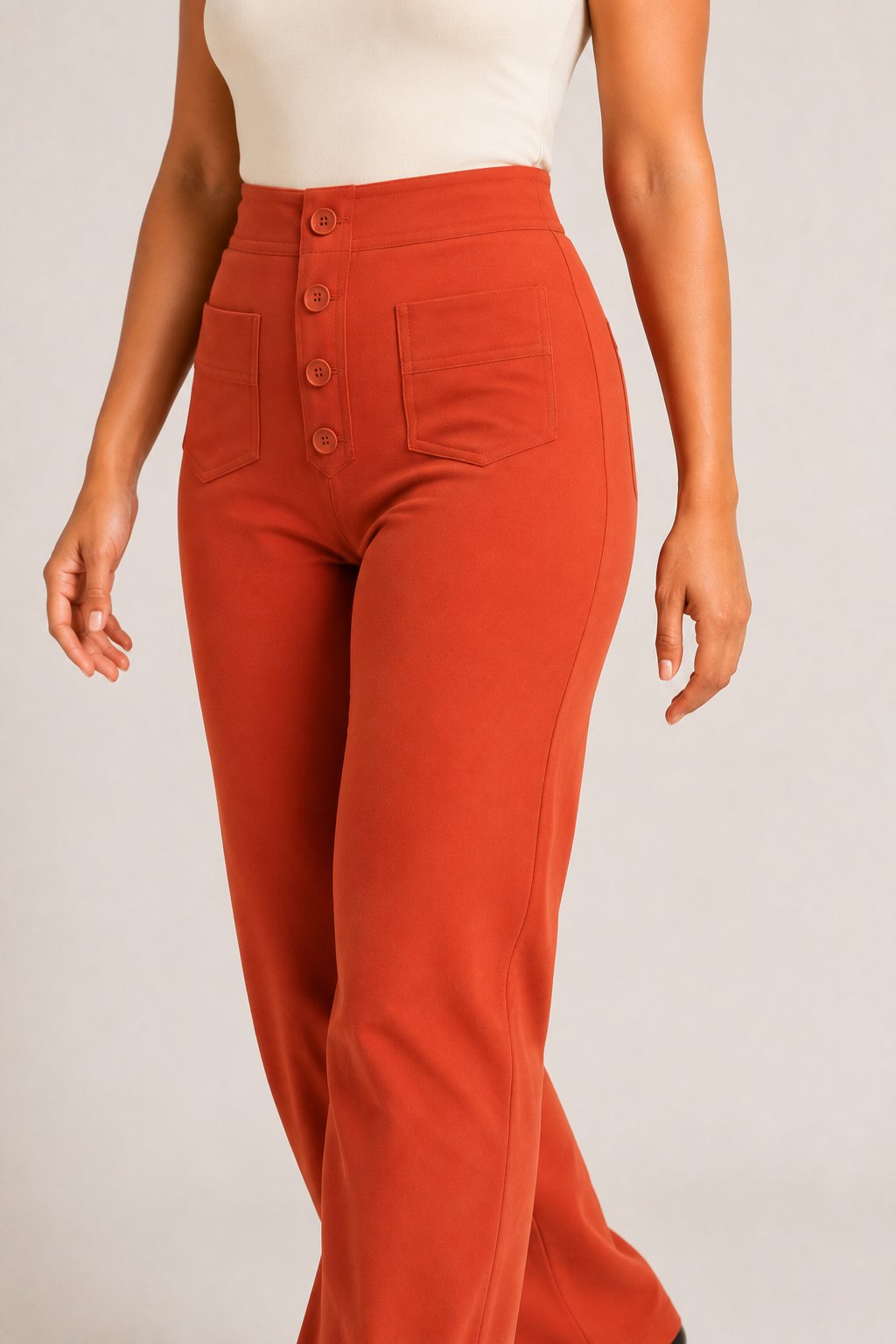 Model-worn close-up of the orange trousers showing the fine matte fabric texture and tonal stitching