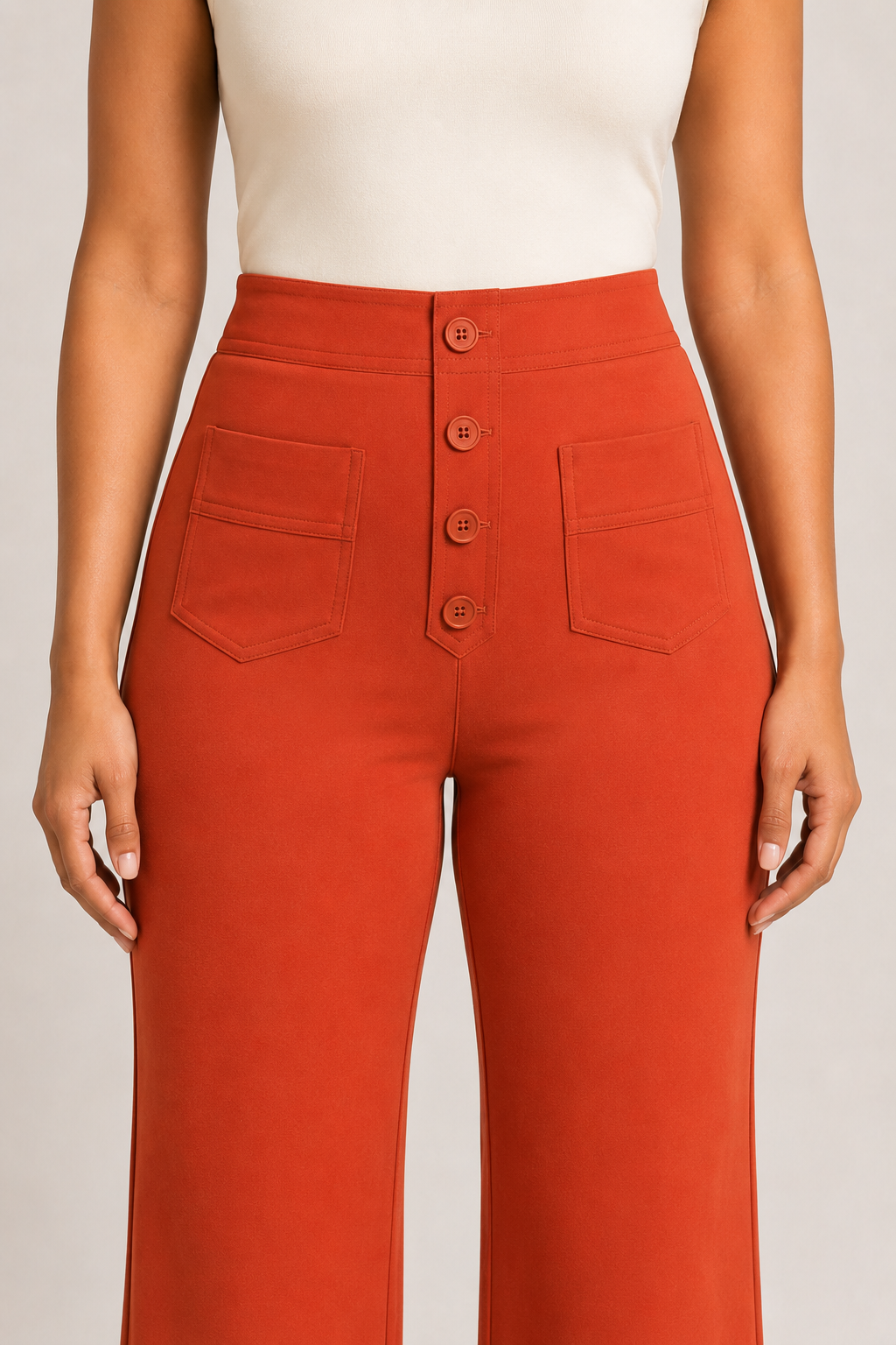 Close-up of the orange trousers showing the four-button front placket, high waistband and patch pockets