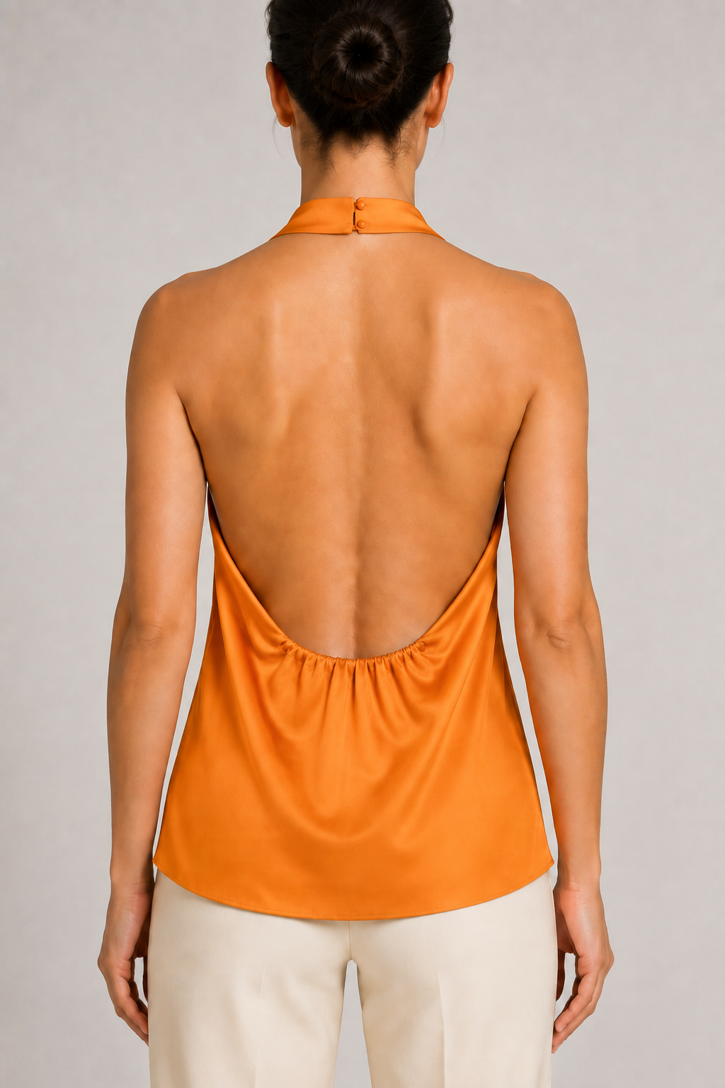 Back close-up of the orange halter top showing the neck fastening, open back and gathered lower edge