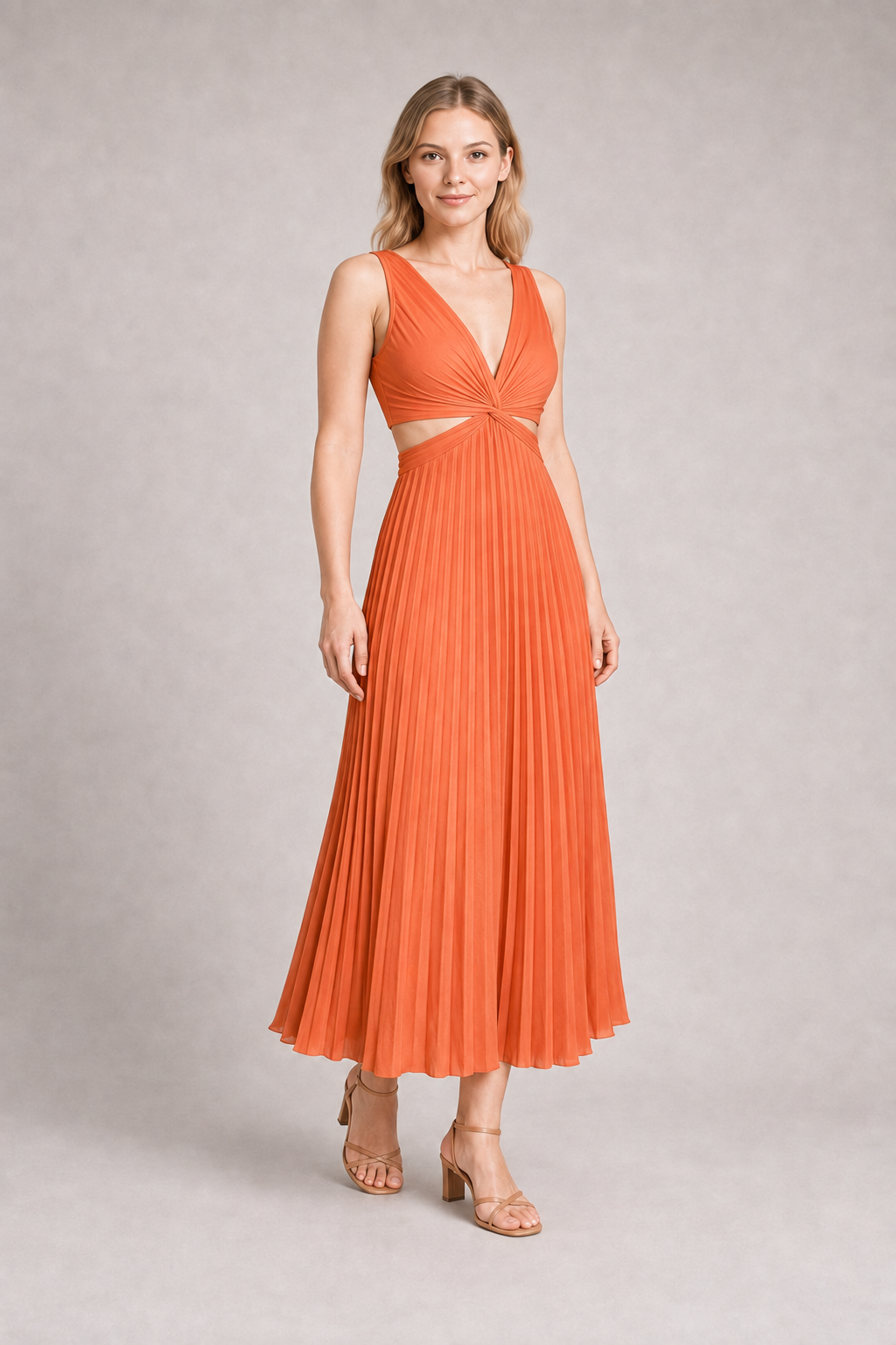 Woman wearing the watermelon-red flowing pleated maxi dress, front three-quarter view