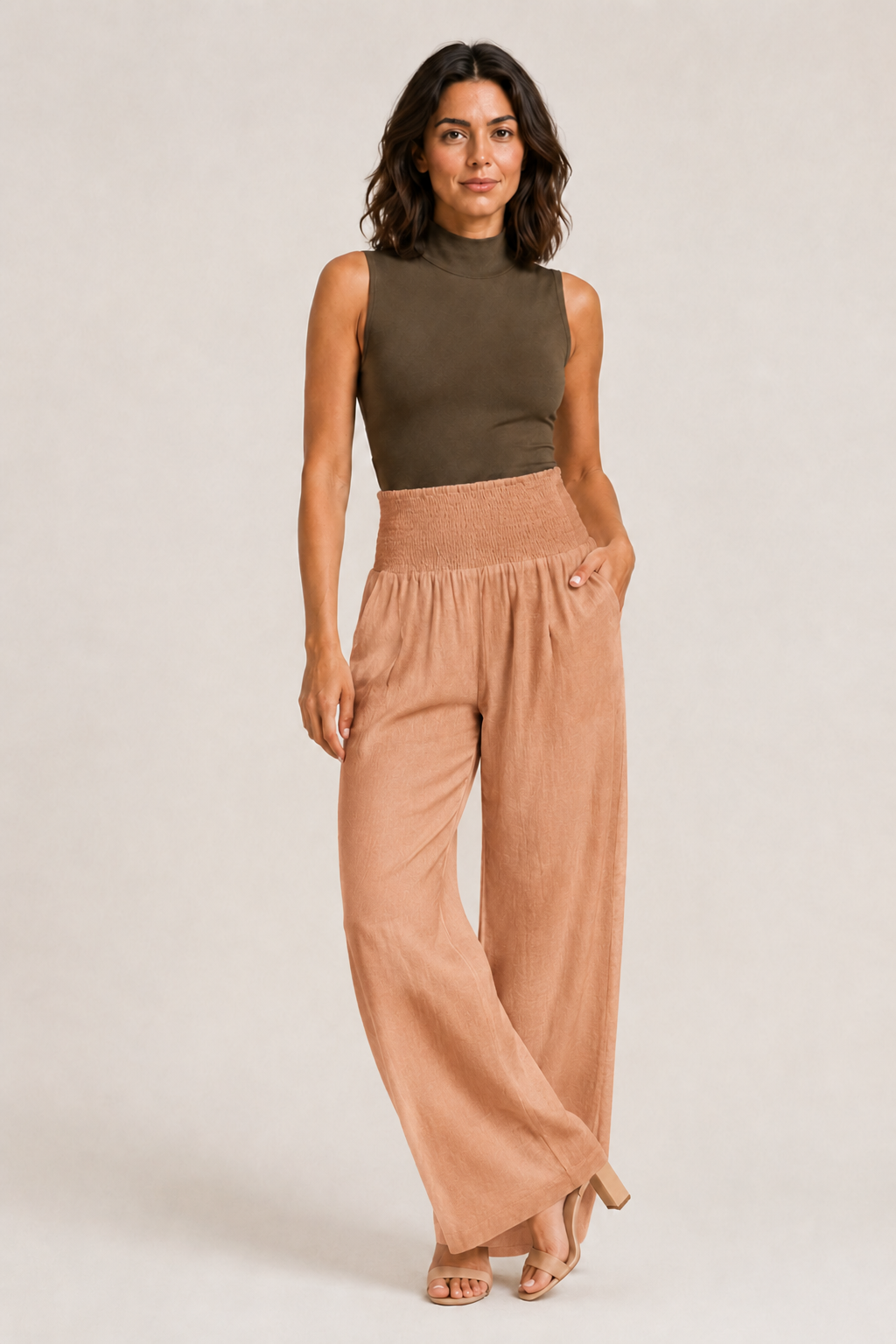 Woman wearing the light orange high-waisted palazzo trousers, front three-quarter view