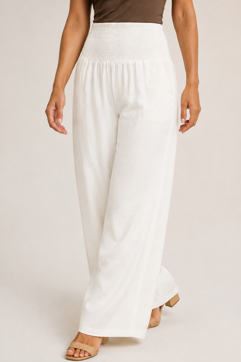 Model-worn close-up of the white palazzo trousers showing the fluid fabric and soft drape
