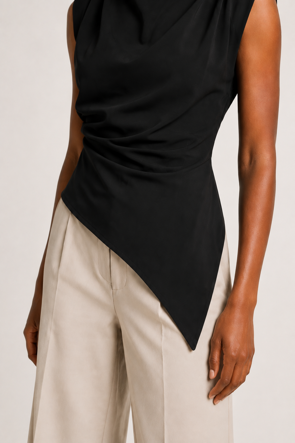 Black sleeveless draped asymmetric top, ruched waist and asymmetric hem construction detail